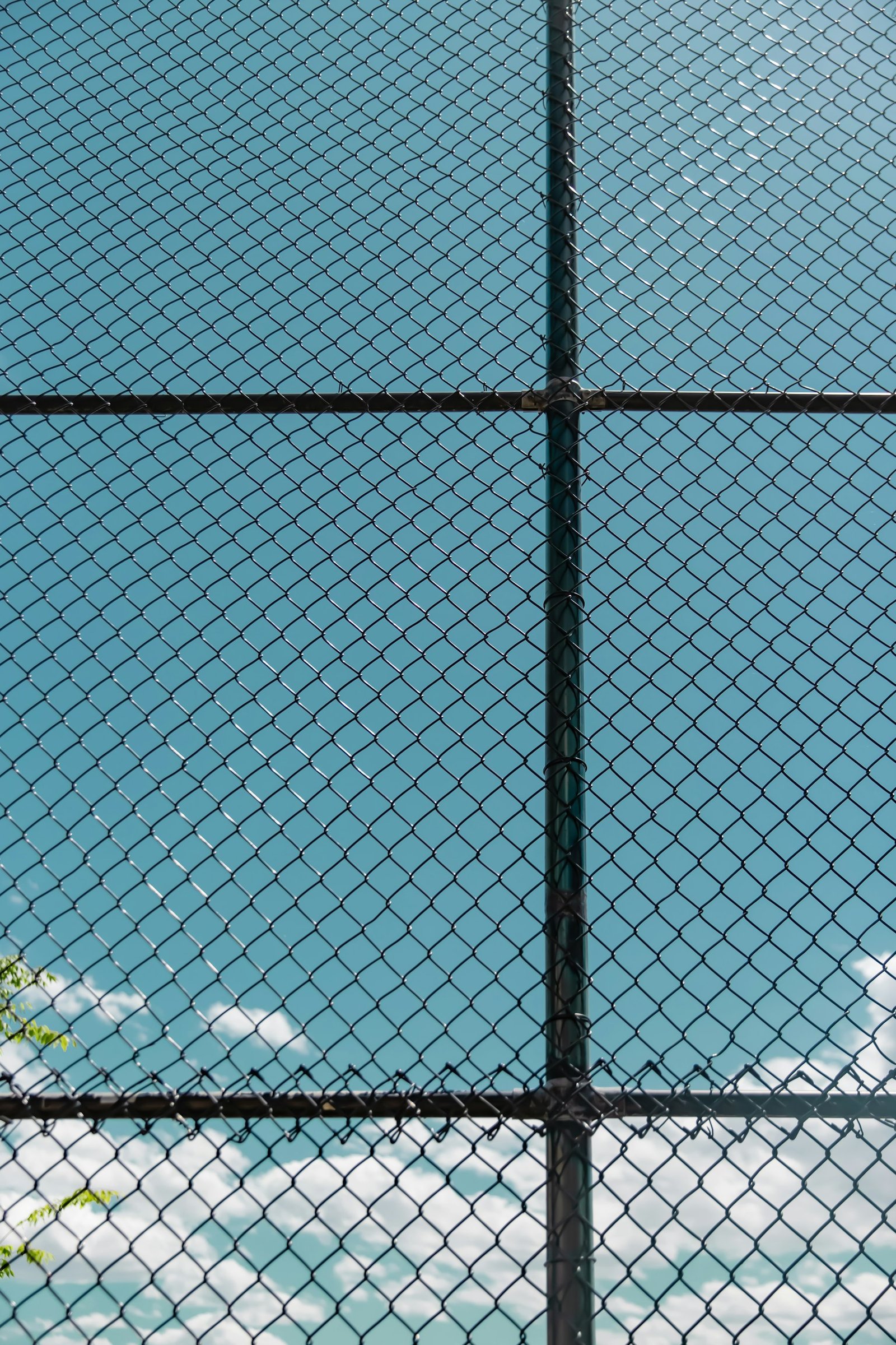 Chain link fence topped with barbed wire, the sea behind it
