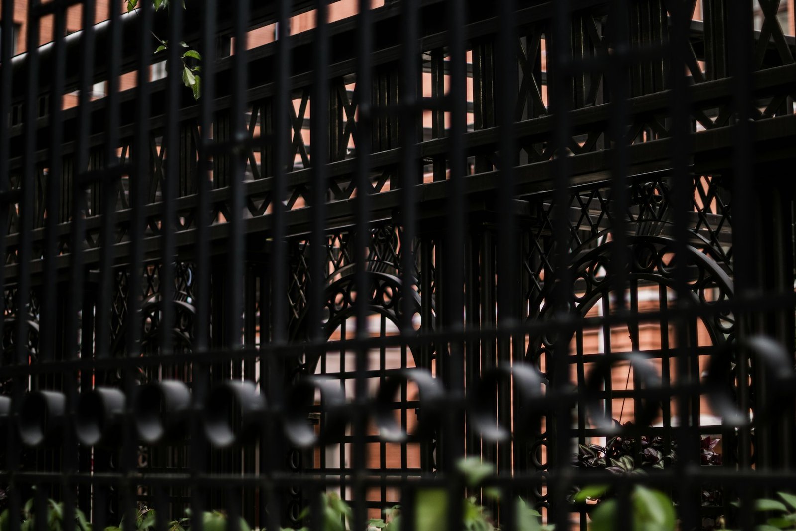 Black metal gate standing in front of an ornate wrought-iron screen
