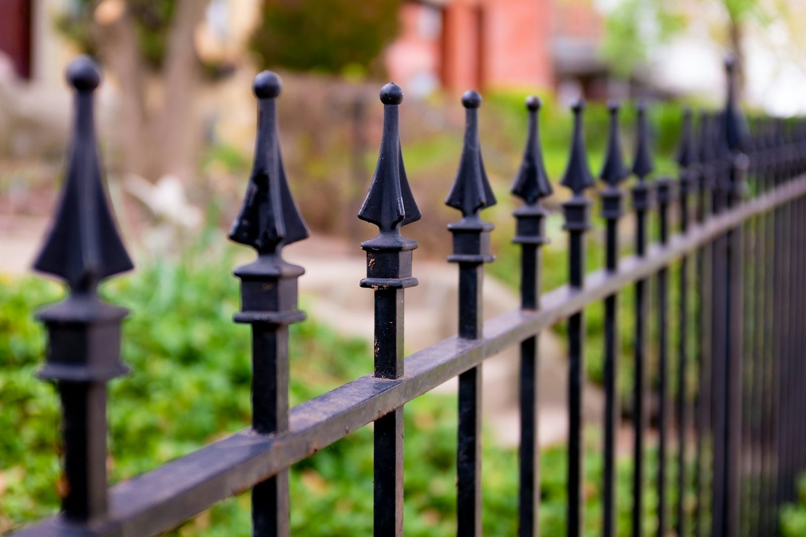 Row of black cast-iron railings with spear finials, in a park